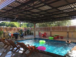 an outdoor pool with a pergola and chairs and a table at Baan Sea Cream in Haad Chao Samran
