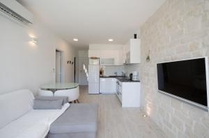 a living room with a white couch and a kitchen at Apartments Zorka in Lopar