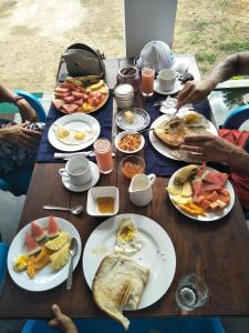 une table en bois avec des assiettes de nourriture pour le petit-déjeuner dans l'établissement Bella Nilaveli Beach, à Nilaveli