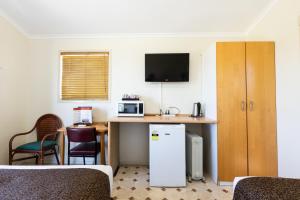 a room with a bed, desk and a television at Hotel Settlers in Biloela