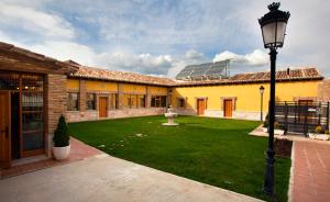 a courtyard with a building with a lawn and a street light at Villa Ferrera Posada Rural in Herrera de Valdecañas
