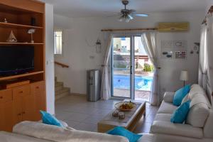 a living room with a couch and a tv and a pool at Villa Charlotte in Protaras