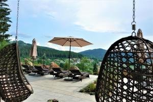 eine Terrasse mit Stühlen und einem Sonnenschirm mit Aussicht in der Unterkunft Montara Suites Bodenmais in Bodenmais