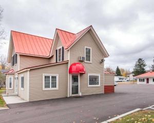 a house with a red roof with a parking lot at Econo Lodge in Saint Albans