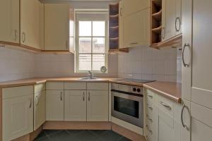 a kitchen with white cabinets and a sink and a window at Oosterhouse in Zandvoort