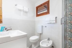 bagno bianco con servizi igienici e lavandino di Hotel Giardino a Capoliveri
