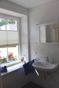 baño blanco con lavabo y ventana en Pension Am Ziegelwall, en Bautzen