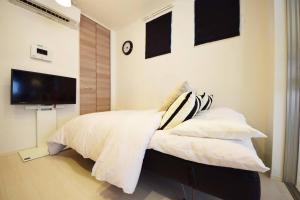 a bedroom with a bed with white sheets and a flat screen tv at Three Tokyo 101 in Tokyo