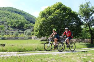 two people riding bikes down a road at Le Chalet de l'Uzège - Piscine, détente et ballades in Belvézet