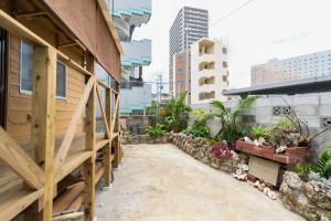 a walkway next to a building with plants at 沖縄古民家お宿ななつぼし Okinawa Traditional House Nanatsuboshi in Naha