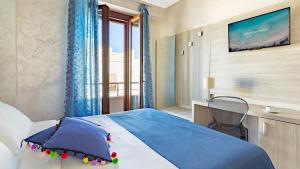 a bedroom with a bed and a tv on a wall at Hotel Piccolo Mondo in San Vito lo Capo