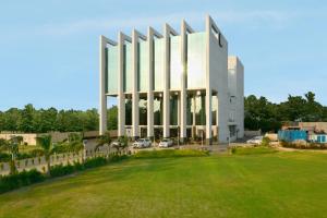a large white building with a green field in front at Hotel Sandy's Tower in Bhubaneshwar