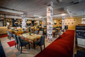 restauracja z drewnianymi stołami i krzesłami oraz czerwonym dywanem w obiekcie Grand Hotel Mustaparta w mieście Tornio