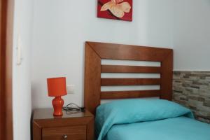 1 dormitorio con 1 cama con cabecero de madera y lámpara en Apartamento para 3 en el centro, en Conil de la Frontera