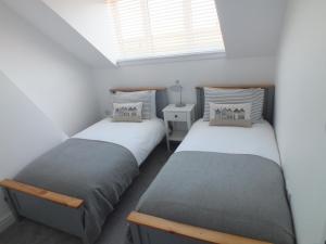 two twin beds in a room with a window at Beyond the Harbour in Whitby