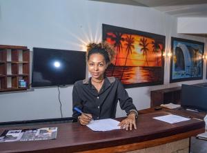 a woman sitting at a desk writing on a piece of paper at Hotel La Bombonera in Nosy Be
