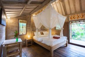 a bedroom with a bed with a mosquito net at Pande Homestay in Canggu