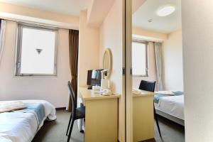 ein Hotelzimmer mit 2 Betten, einem Schreibtisch und einem Spiegel in der Unterkunft Hotel Frontier Iwaki in Iwaki + 11 Fotos