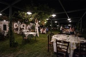 a woman standing under a tent with tables and chairs at Agriturismo Giardino di Iti in Rossano