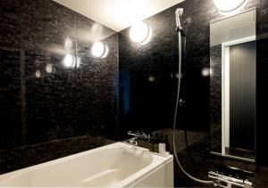 a black bathroom with a tub and a mirror at Sonezaki Luxe Hotel in Osaka