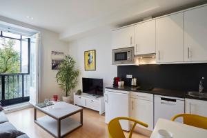 kuchnia z białymi szafkami i salonem w obiekcie LEEWAYS APARTMENT III in ALCALÁ 99 w Madrycie
