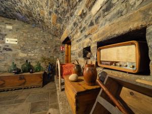 Habitación con una pared de piedra con jarrones sobre una mesa. en Casa Dueso en El Pueyo de Araguás