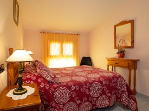 um quarto com uma cama vermelha e uma mesa com um candeeiro em Apartamento Casa Dueso em El Pueyo de Araguás