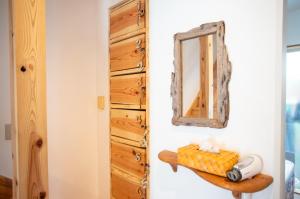 un miroir sur un mur à côté d'une commode en bois dans l'établissement Katsuo Guest House, à Kōchi