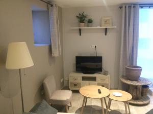 Chez Adeline في Céreste: غرفة معيشة مع تلفزيون وطاولة وكراسي