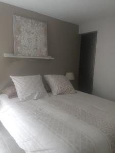 a bedroom with a bed with white sheets and pillows at Chez Adeline in Céreste