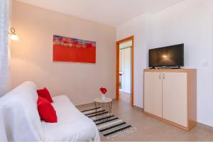 een woonkamer met een witte bank en een flatscreen-tv bij Red Apartment in Vrsar