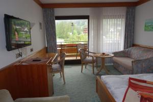 a room with a living room with a couch and a tv at Hotel Hirsch mit Café Klösterle in Enzklösterle