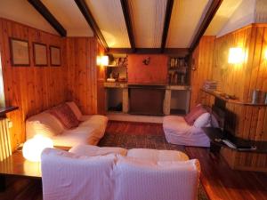 una sala de estar con paredes de madera y sofás blancos. en Appartamento La Primula, en Madesimo