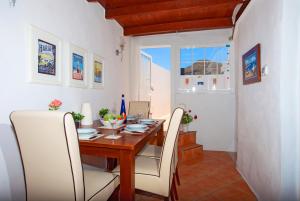 une salle à manger avec une table en bois et des chaises blanches dans l'établissement Eco Casa Atalaya, à Máguez