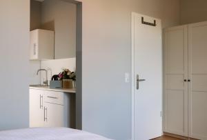 a white kitchen with white cabinets and a door at Stadt Apartments Burg Fehmarn in Burg auf Fehmarn