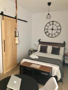 1 dormitorio con 1 cama y reloj en la pared en Apartamentos RuiSol - AUTO CHECKIN - by Centrall alquileres turísticos, en Nerja