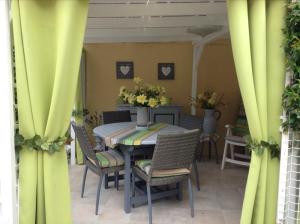 une salle à manger avec des rideaux jaunes, une table et des chaises dans l'établissement La Maison s'apelle le P'tit Nid, à Granville