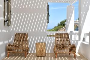 two rattan chairs on a porch with a view of the ocean at Ciel Villas Paros in Pounda