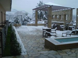 eine schneebedeckte Terrasse mit Tischen und Stühlen in der Unterkunft Dovitel Boutique Hotel in Ioannina