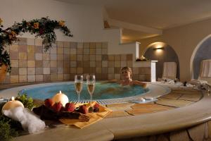 une femme dans un bain à remous avec des verres de vin dans l'établissement Hotel Sole, à Malè