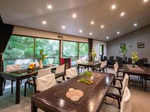 a restaurant with tables and chairs and large windows at Hakone Onsen Sanso Nakamura in Hakone