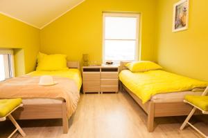 2 camas en una habitación con paredes amarillas en "U Mamy Róży" - Pokoje Gościnne, en Reda