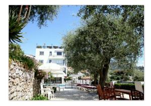 a tree and some tables and chairs and a building at Hôtel Le Versailles in Villefranche-sur-Mer