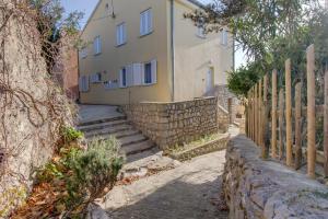 a house with a stone wall next to a fence at Apartment Mikic in Čunski