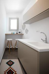 uma cozinha branca com um lavatório e um banco em Mellow Luxury Cave em Oia mais 22 fotografias