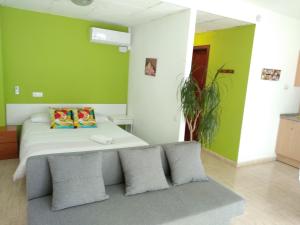 1 dormitorio con paredes verdes y 1 cama con almohadas en Estudio en el centro 0, en Reus
