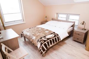 a bedroom with a bed and a desk and two windows at "U Mamy Róży" - Pokoje Gościnne in Reda