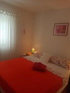 a bedroom with a bed with a red blanket at Apartment Novaković in Mirce