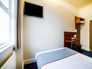 ロンドンにあるThe Park Hotelのベッドと壁にテレビが備わるホテルルームです。