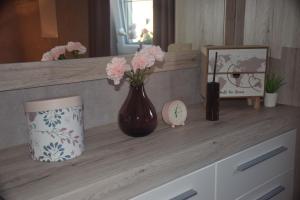 un comptoir avec un vase avec des fleurs roses sur lui dans l'établissement Echappée Belle, à Jalhay